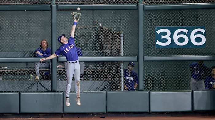 Rangers’ Evan Carter makes a leaping grab at the wall vs. Astros.